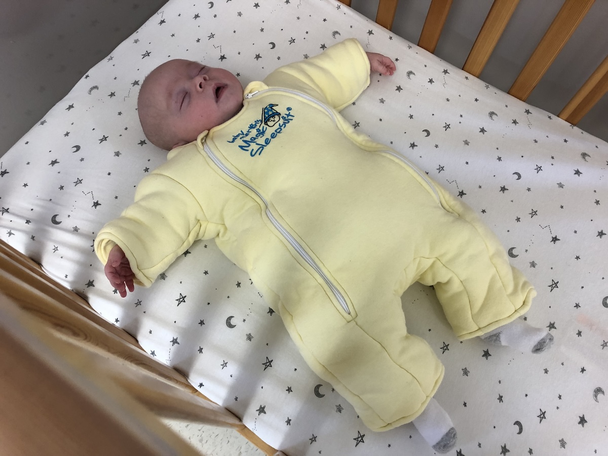 Newborn Essentials Checklist: Baby sleeping in magic merlin sleep suit 